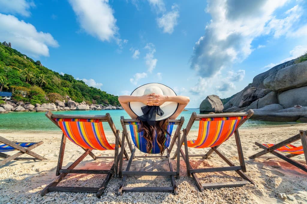 Femeie relaxându-se pe un șezlong la plajă
